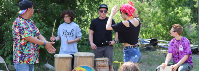 Youth standing around and dancing outside with large bongo drums