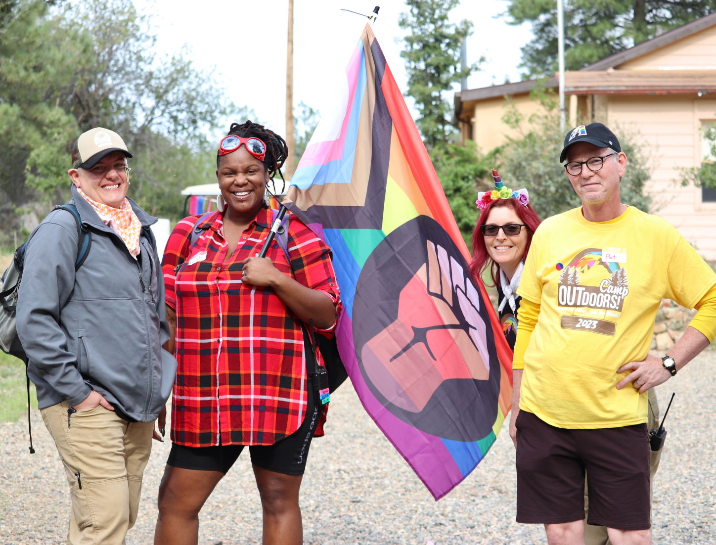 Parents and trusted adults at Camp Outdoors holding a rainbow flag