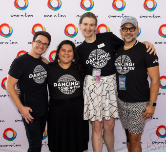 4 people with dancing one•n•ten shirts on posing in front of a branded backdrop