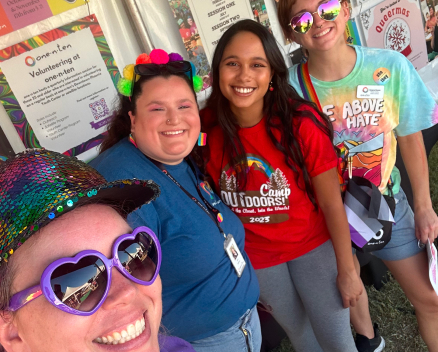 LGBTQ youth standing in front of a camp outdoors bulletin board