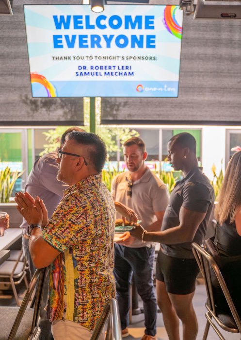 TV screen welcoming guests to a fundraiser with people mingling