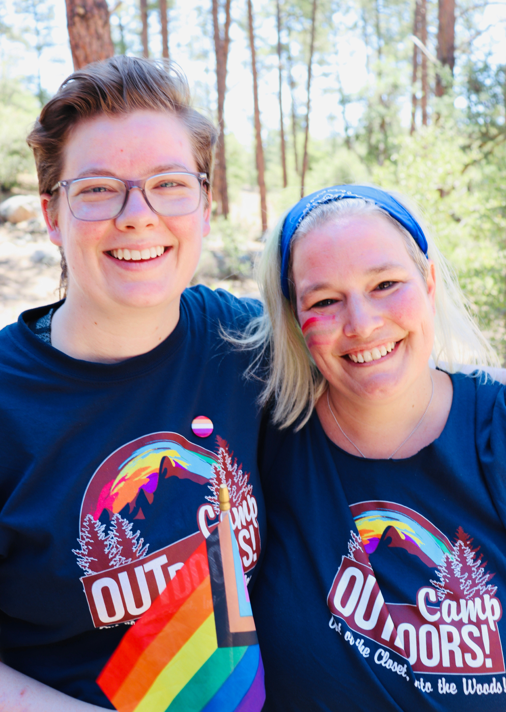 Two Camp Outdoor attendees in navy shirts posing in the pines