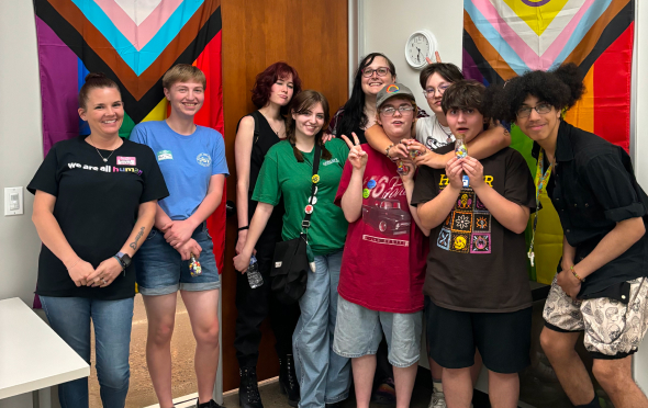 Group of teens posing in front of LGBTQ flags