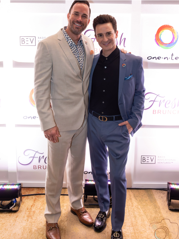 Two one•n•ten leaders posing in front of a branded, backlit backdrop