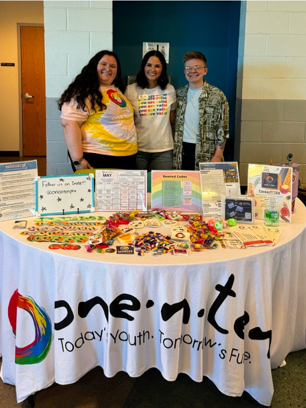 organization volunteers standing in front of a round table draped in a one•n•ten white tablecloth covered in small give aways