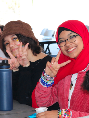 Two young Asian's smiling and gesturing peace symbols