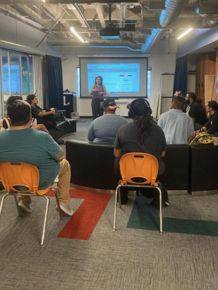 people sitting and listening to a presenter at the front of the room