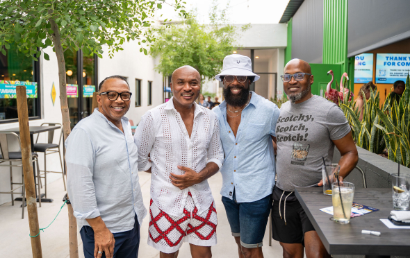 Four black men standing together and posing at a fundraiser event