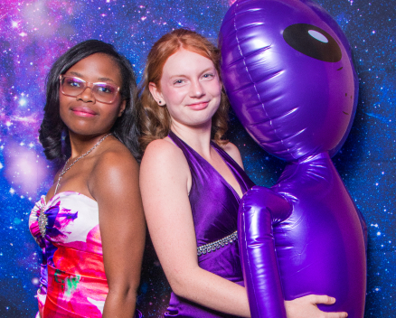 Two teen girls dressed up and posing with alien at queer prom